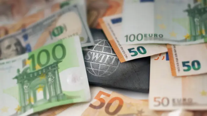 شعار نظام "سويفت" وعدد من العملات