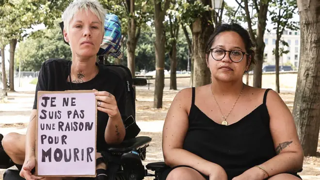 Protesters in wheelchairs with a sign that says in french ' I am not a reason to die"