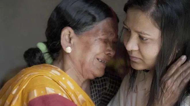 पीली साड़ी पहनी हुईं सीरो देवी जो मोनिका को पकड़ कर रो रही हैं. 