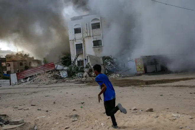 Um jovem corre para se proteger após um ataque aéreo durante uma operação militar israelense na Cidade de Gaza, em 3 de outubro de 2025.