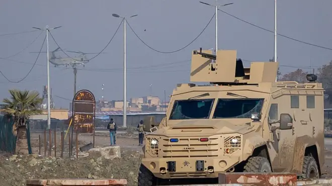 24 Ocak 2026'da Suriye'nin Haseke kentindeki IŞİD üyelerinin tutulduğu bir hapishaneye ABD'ye ait bir Chinook helikopteri iniş yapıyor. Odakta zırhlı silahlı bir araç var. 