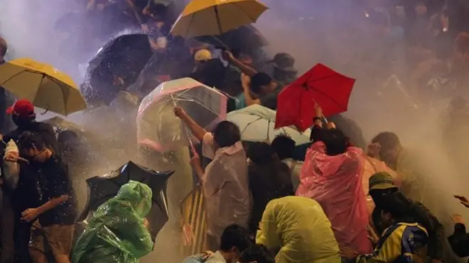 Pro-democracy protesters react as riot police fire water canons during an anti-government protest in Bangkok, Thailand, 16 October 2020.