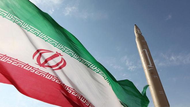 العلم الإيراني وإلى جواره صاروخ إيراني الصنع