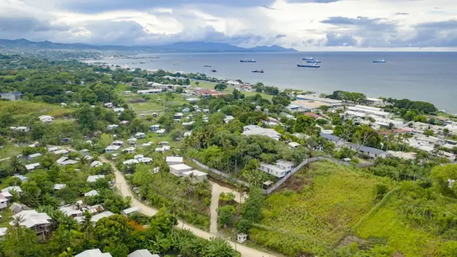 An aerial view of houses and a bay with ships in the Solomon Islands