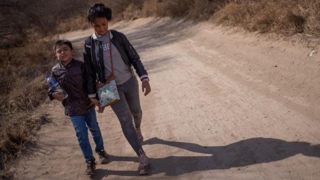 Dos niños hondureños caminan en una carretera de tierra en Peñitas, Texas, después de cruzar la frontera a través del Río Bravo.
