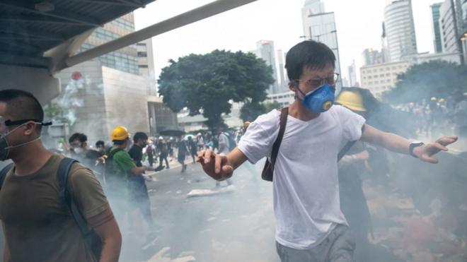 Демонстрант у масці тікає від сльозогінного газу