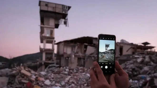 أحدهم يصور أطلال بناء بهاتف ذكي