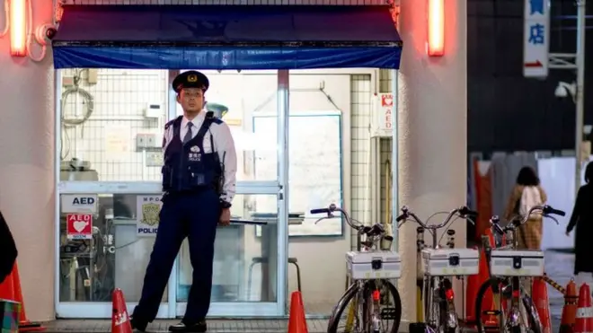 Un policier observe les passants et les acheteurs depuis sa cabine de police le long de l'avenue Omotesando à Tokyo