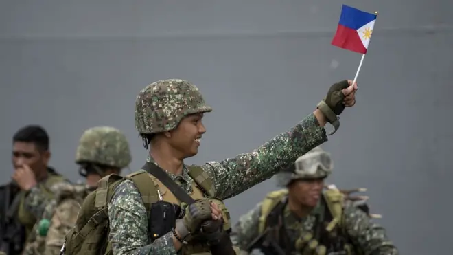 Tentara Filipina memegang bendera setibanya di Manila pada 30 Oktober setelah menyelesaikan tugas di Marawi.