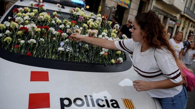 A woman displays a flower on the windshield of a vehicle of Catalan police, known as Mossos d'Esquadra during a pro-referendum rally in Barcelona on September 24, 2017.
