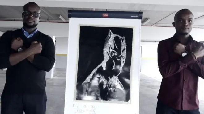 Artists dey stand near dia painting