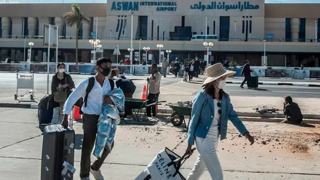 Les passagers, portant des masques, quittent l'aéroport international d'Assouan en Egypt.