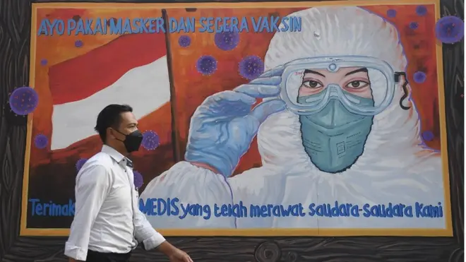 Warga melintas di dekat mural bertema Covid-19 di Jakarta, Rabu (1/12/2021).