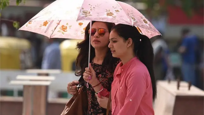 వేసవి నుంచి రక్షణకు గొడుగులో వెళ్తున్నవారు