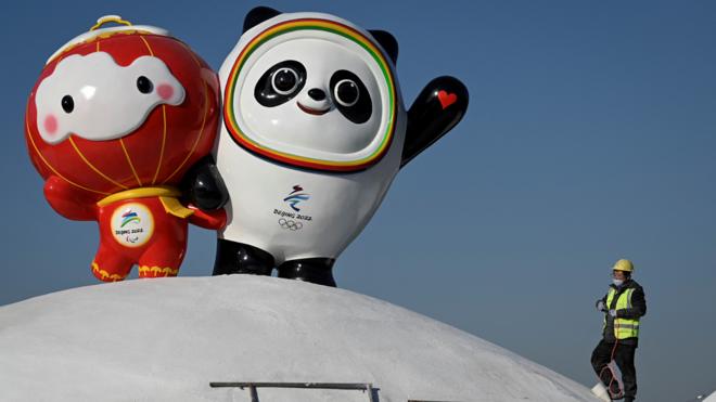 Operário monta instalação exibindo mascotes dos Jogos Olímpicos e Paralímpicos de Inverno de Pequim 2022, em uma rua em Pequim, em 11 de janeiro de 2022