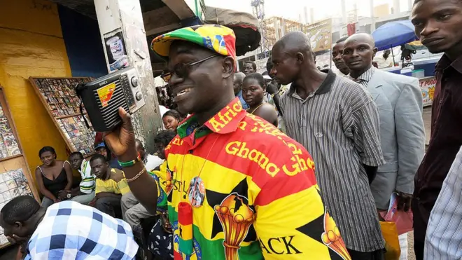 Ghanaians dey listen to radio well-well; dis football fan dey hear match between Nigeria and Ghana