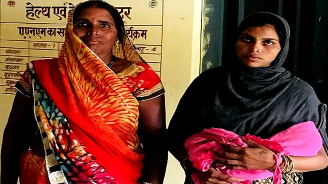 नवजात शिशु और अपनी माँ के साथ बिना मास्क के खड़ी मोहनपुरा गाँव की निवासी नीलम