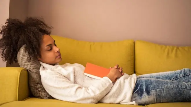 فتاة نائمة وهي تمسك بكتاب