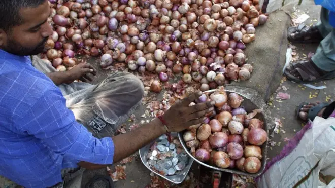 શાક માર્કિટમાં ડુંગળી વેંચી રહેલો શાકવાળો