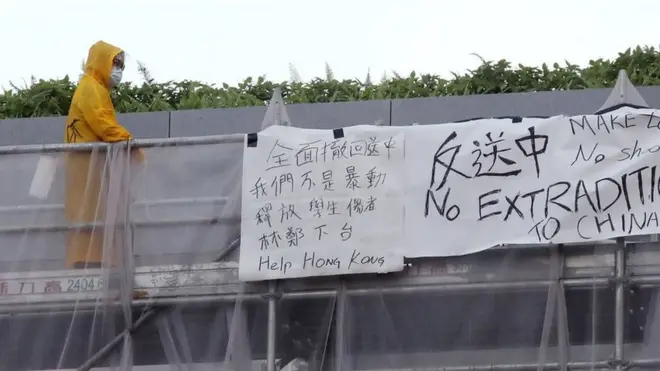 身穿黄色雨衣的梁凌杰当天危站多个小时，之后他堕楼身亡。