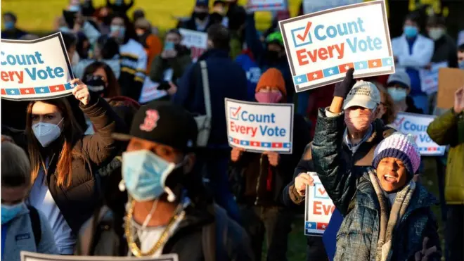 protesters holding signs saying every vote counts