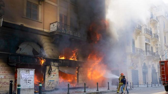 رجال الإطفاء اللبنانيون يحاولون إخماد حريق أشعله محتجون في أحد المصارف في مدينة طرابلس