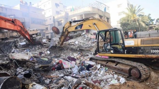 Экскаваторы разгребают обломки здания в Газе, разрушенного изральским авиаударом