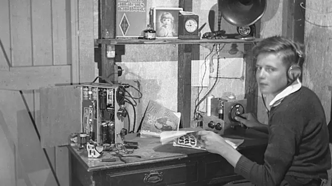 David pictured as a boy, wearing headphones and using his radio equipment