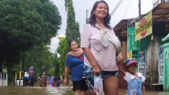Seorang ibu dan anak melewati banjir di Jakarta Selatan, Selasa (25/02).