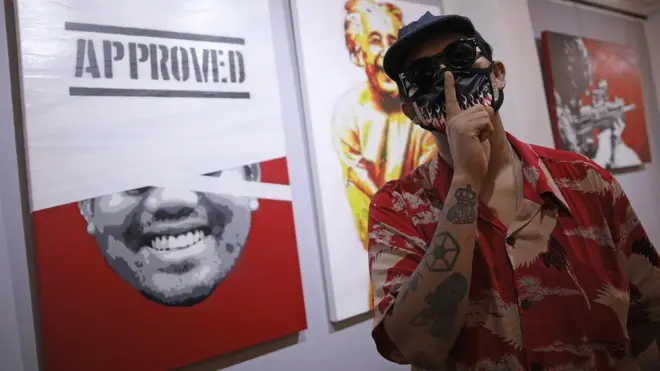 เฮดเอค สเตนซิล กับผลงานที่นำมาจัดแสดงในนิทรรศการศิลปะ "ดู-ดาย Do or Die"