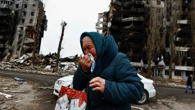 Umugore urira arimo kugenda iruhande rw'inyubako zashenywe n'ibisasu by'Uburusiya mu gace ka Borodyanka mu mujyi wa Bucha, ku itariki ya 5 y'ukwezi kwa kane mu 2022