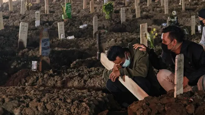 Seorang pria menangis di makam kerabatnya di lahan pemakaman penderita Covid-19 di TPU Rorotan Jakarta.