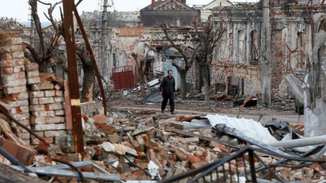 A man walks near damaged buildings in the course of Ukraine-Russia conflict in the southern port city of Mariupol, Ukraine April 22, 2022. REUTERS/Alexander Ermochenko