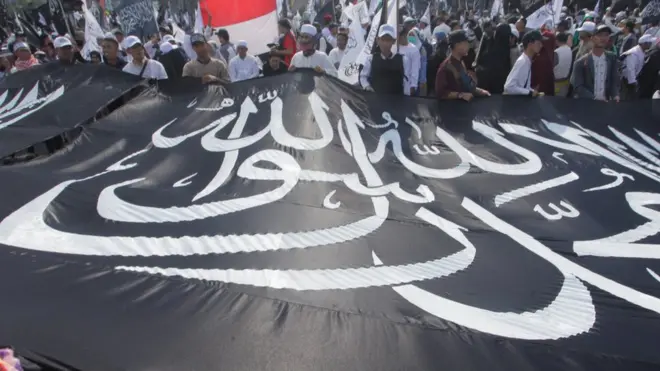 Bendera hitam bertuliskan kalimat tauhid berwarna putih ini dibela sebagai panji Nabi Muhammad di Indonesia, tapi dianggap merujuk pada gerakan ekstremis di Arab Saudi.