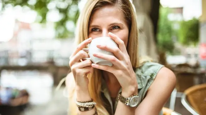 سيدة تركز النظر أمامها وهي تشرب فنجانا من الشاي