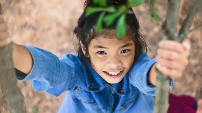 Una niña tailandesa jugando en un árbol