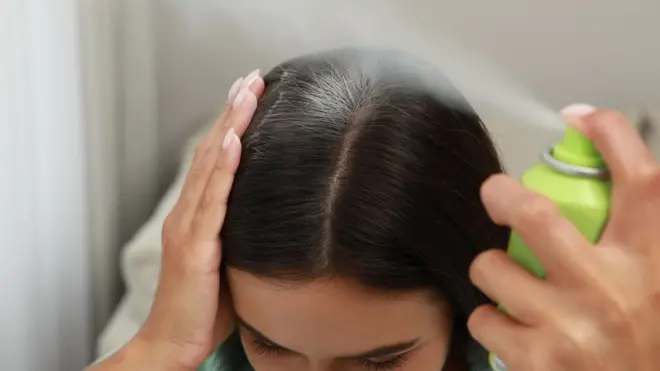 Mulher aplicando xampu a seco no cabelo
