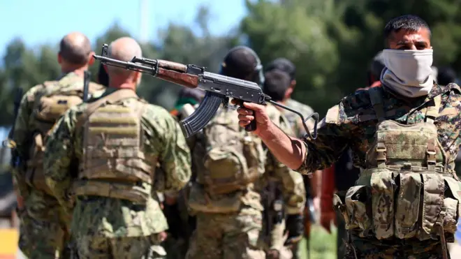 Бойцы курдского ополчения на месте авиаудара, нанесенного турецкими ВВС невдалеке от населенного курдами города Дерик на северо-востоке Сирии