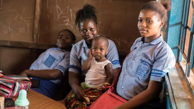 Emma sits with a small child