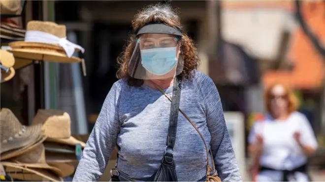 A woman in a mask and face shield is pictured in California