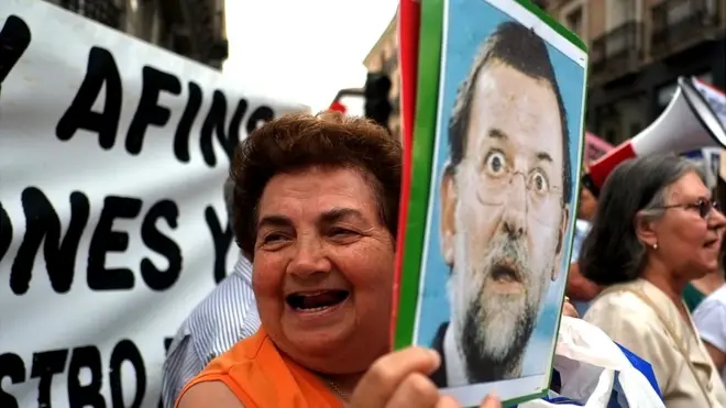 Una mujer sostiene una foto de Mariano Rajoy en medio de una marcha para exigir la renuncia del presidente de gobierno.