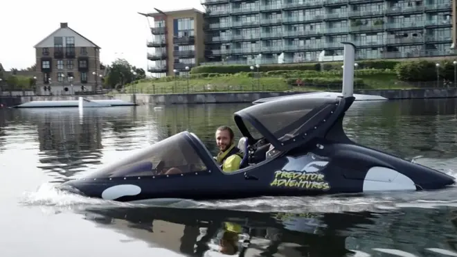 Адам Букаускас показывает лодку-касатку журналистам.