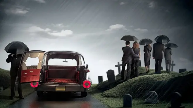 Staged picture of a funeral procession with a group of mourners standing in the rain