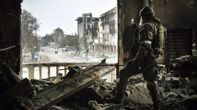 Російський солдат патрулює у квітні Маріупольський драмтеатр, розбомблений 16 березня