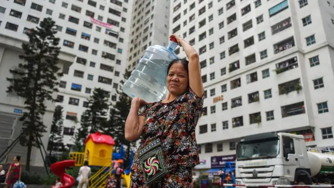 Một phụ nữ ở Hà Nội lấy nước cung cấp từ xe bồn về nhà