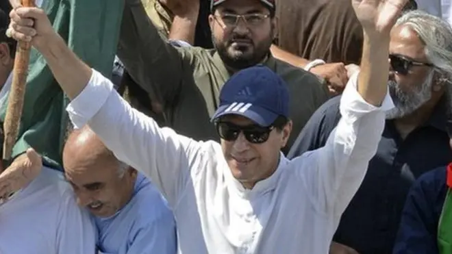 عمران خان لانگ مارچ کے دوران اپنے حمایتیوں کے نعروں کا ہاتھ ہلا کر جواب دے رہے ہیں