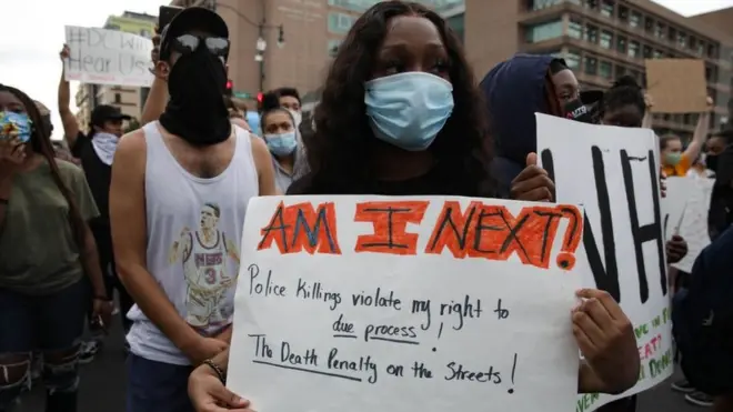 Seorang pendemo membawa poster "Am I Next" dalam unjuk rasa di Washington DC, AS, memprotes keamtian George Floyd, Jumat (29/05).