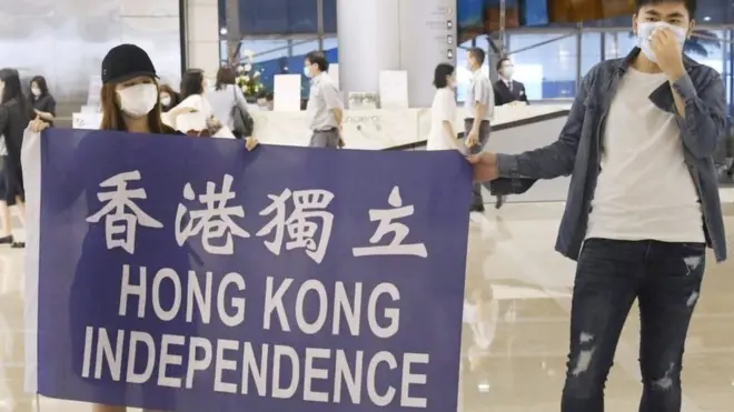 Dua pemrotes membentangkan spanduk bertuliskan 'Hong Kong Independence' pada Senin (25/05) lalu.