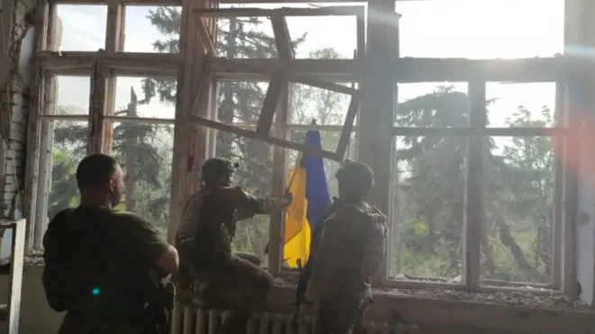 Photo montrant des soldats ukrainiens plaçant un drapeau national ukrainien sur un bâtiment détruit dans le village de Blahodatne, dans l'est de l'Ukraine. Photo : 11 juin 2023
