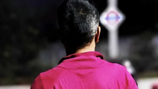 The back of a man's head wearing a pink shirt